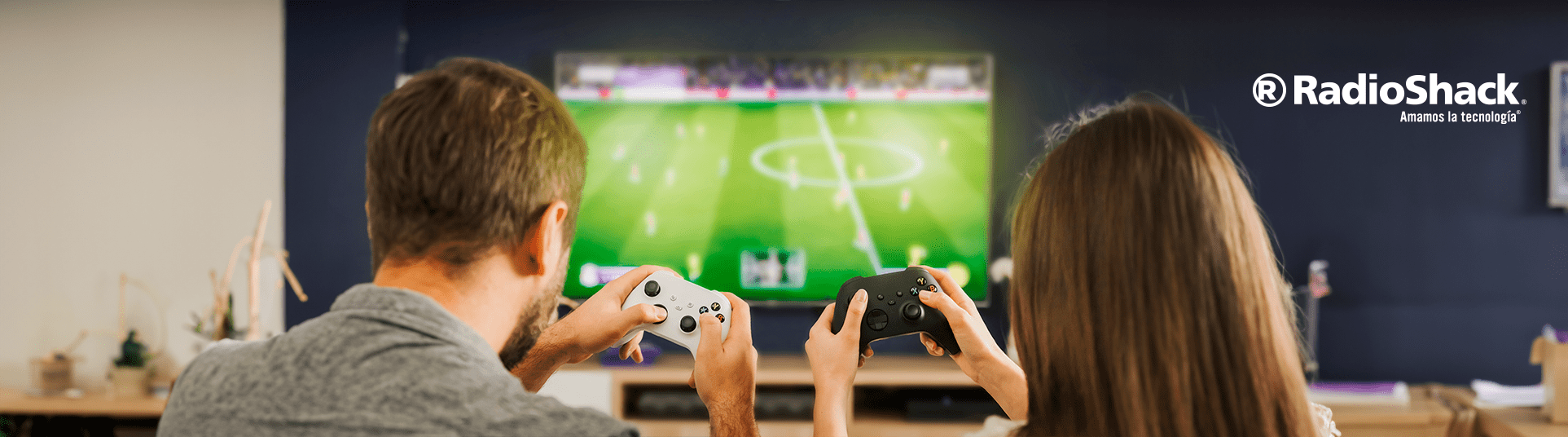 una pareja joven sostiene cada uno un control alambrico y un control inalambrico mientras juegan en su consola xbox one en su sala de estar
